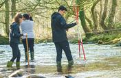 Geography students conducting measurements in a river